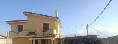 fabbricato con struttura in cemento armato a due piani fuori terra, con copertura a tetto con falde inclinate e con annessa corte e pertinenze esterne.  Al piano terreno si rileva la presenza di una verandina coperta da tetto a falda spiovente, a pianta quadrata collegata al soggiorno mediante una porta balcone. Il piano superiore è caratterizzato dall’ampio “vano” scala che disimpegna verso la camera padronale, una camera, una cameretta ed una seconda sala bagno.