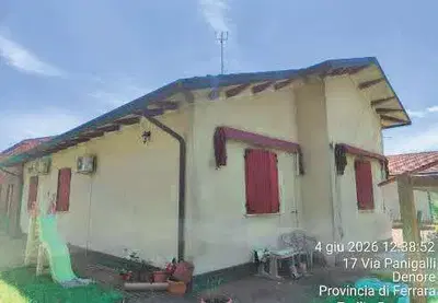 Piena Proprietà di abitazione in villini, sita in Comune di Ferrara (FE) in Via Panigalli 17, costituita da appartamento al piano terra ed adiacente costruzione su due piani allo stato grezzo strutturale, con solo strutture portanti verticali e partizioni orizzontali, parziali strutture divisorie al piano terra e priva di copertura, il tutto con circostante area cortiliva esclusiva recintata. Occupato