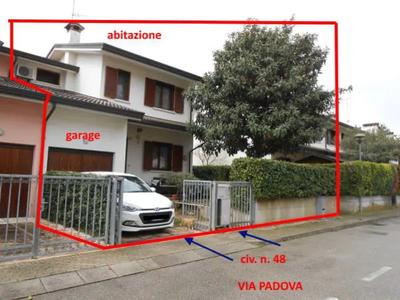 Facente parte di un fabbricato residenziale a schiera, abitazione costituita da ingresso-soggiorno, cucina-pranzo, corridoio, bagno cieco, lavanderia e c.t. al piano terra; disimpegno, studio (ex soffitta), 3 camere e bagno finestrato al piano primo; locali accessori ripostiglio e cantina al piano interrato. Garage pertinenziale al piano terra. Il tutto con annesso scoperto esclusivo pertinenziale a corte/giardino che si estende su 3 lati intorno al fabbricato. Difformità catastali e edilizie.